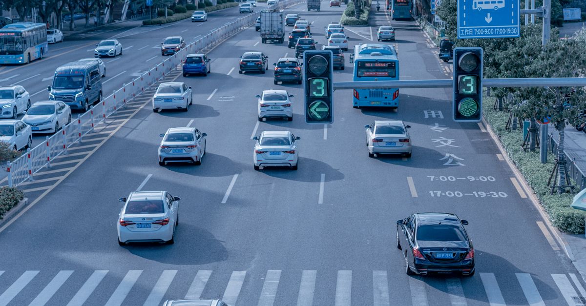 Wide shot of urban traffic at a busy city intersection with cars and buses.